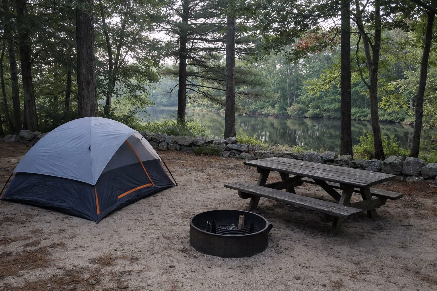 Tent and picnic table at a wooded campsite near a pond