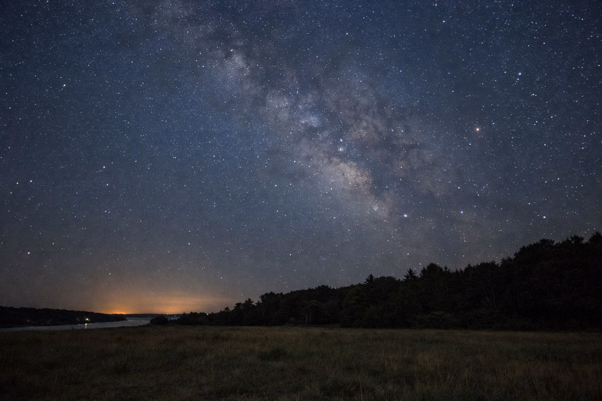 Starry night sky over a dark open field